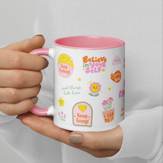 Person holding a mug with motivational phrases and designs on a plain background