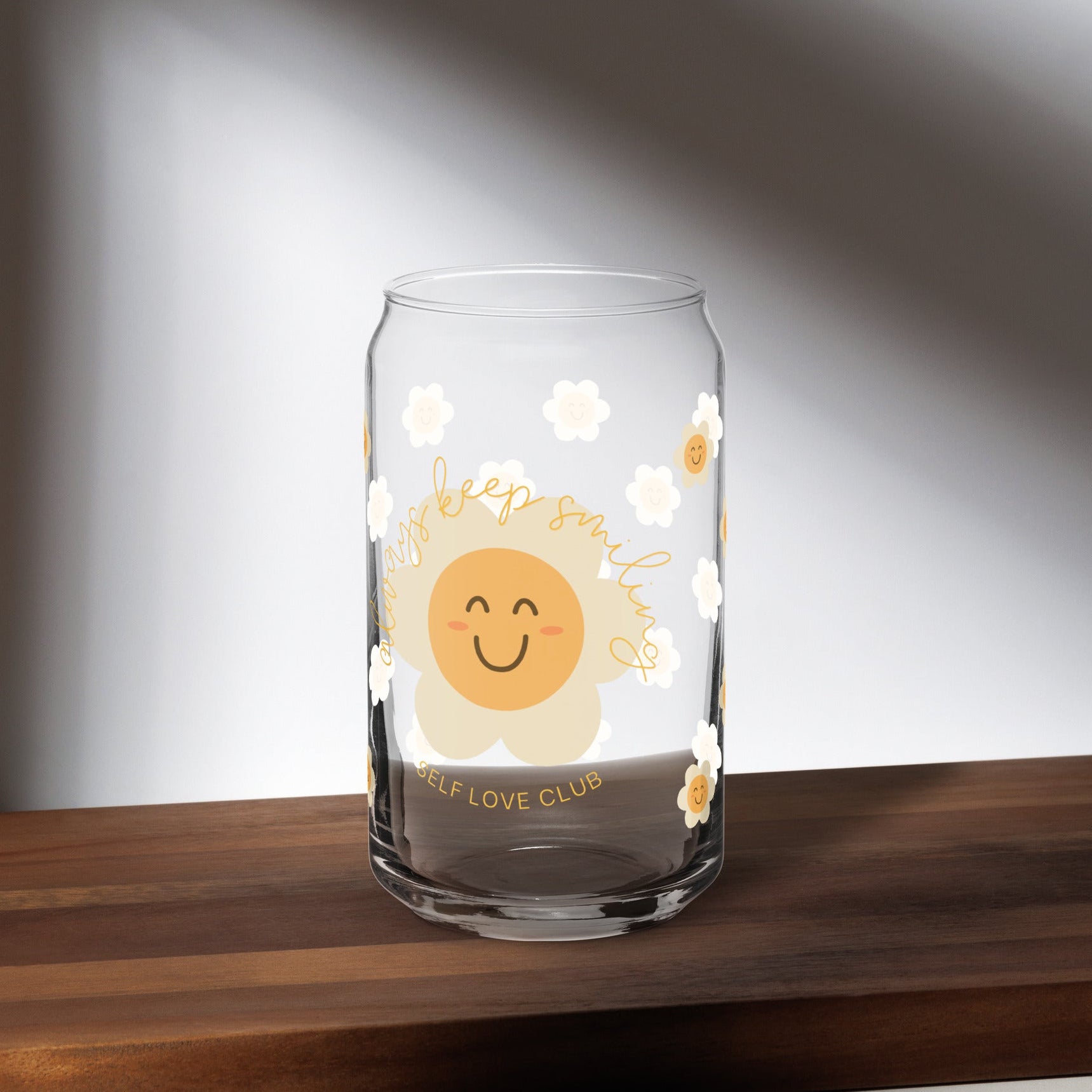 Clear glass mug with a happy flower design on a wooden surface