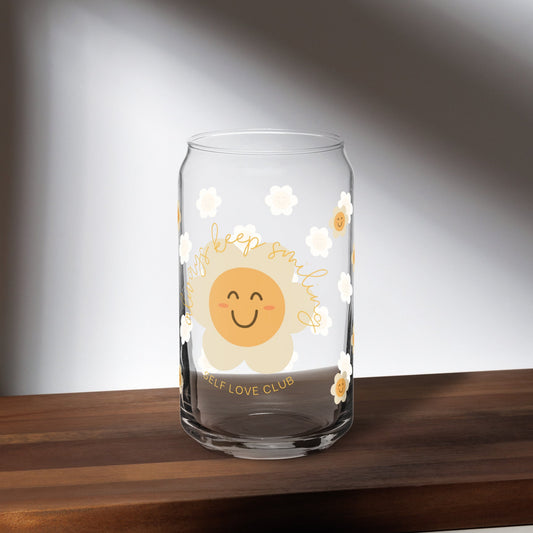 Clear glass mug with a happy flower design on a wooden surface