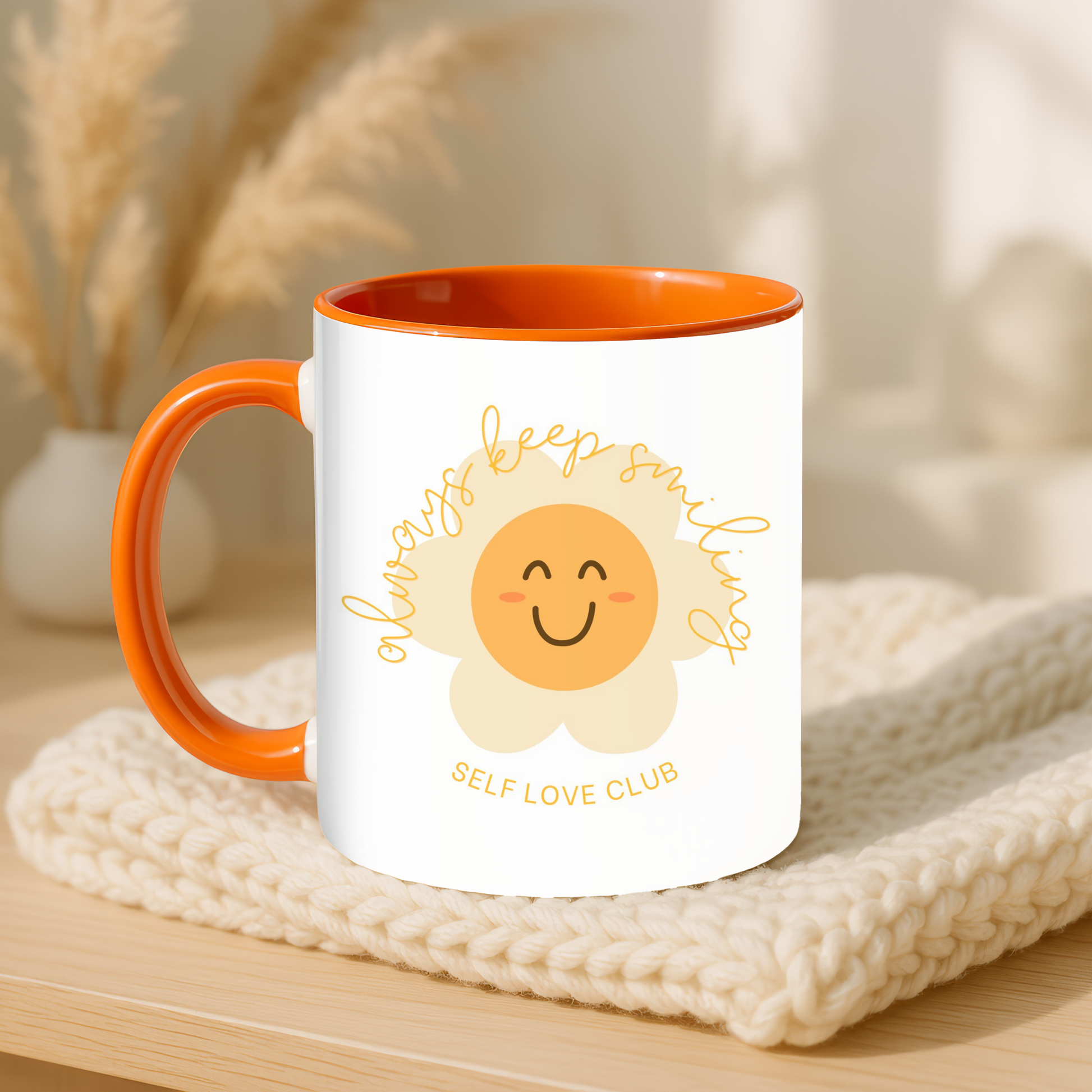 Mug with a smiling flower face design and text on a wooden surface with a blurred background
