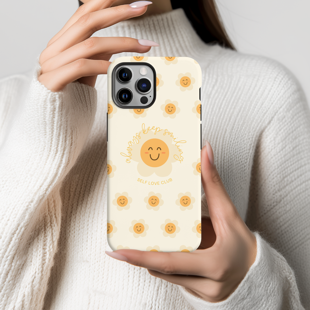 Person holding a phone with a flower-themed case featuring a smiling face design.