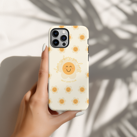 Phone case with happy flower design held by a hand against a neutral background