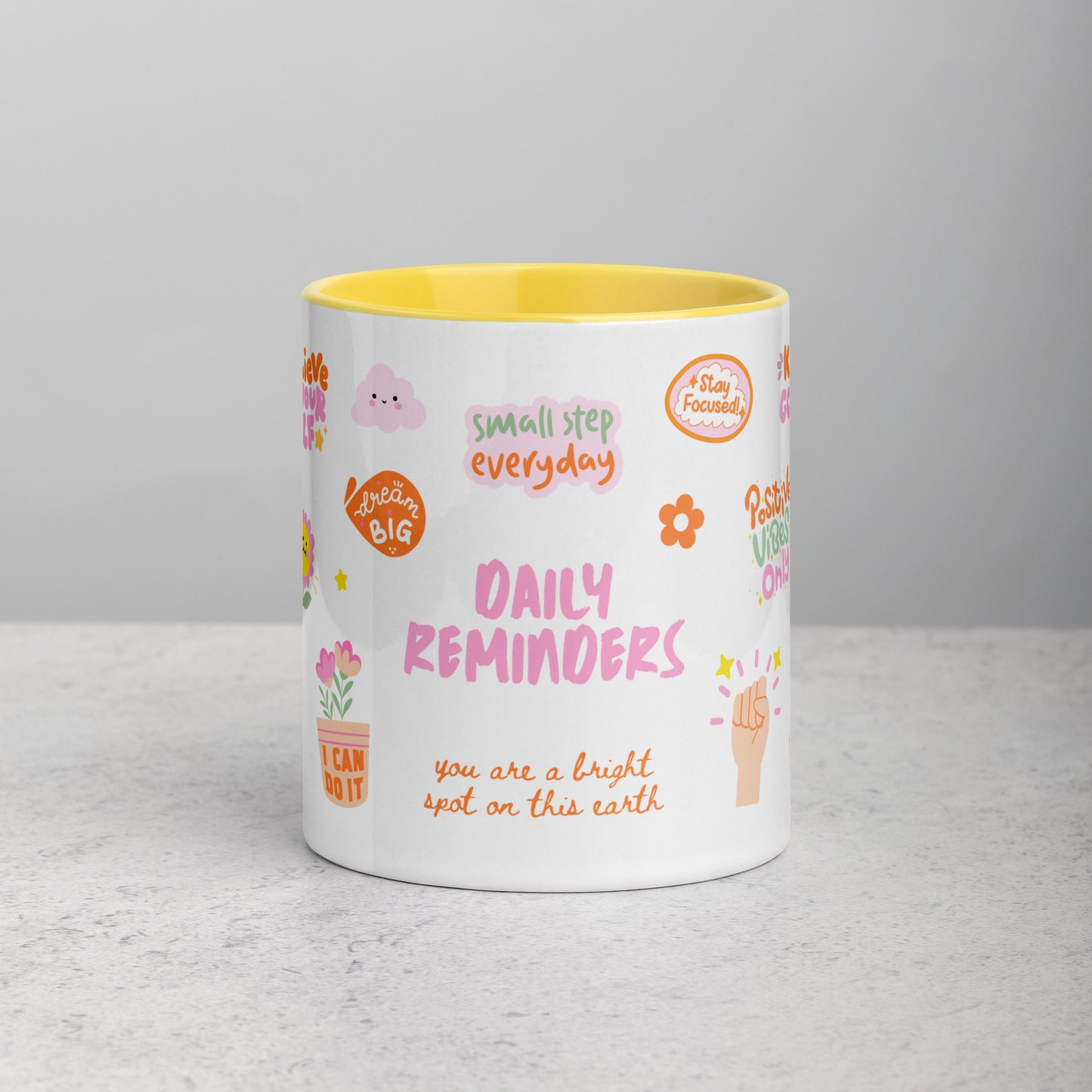 yellow mug with colorful text and graphics on a gray surface