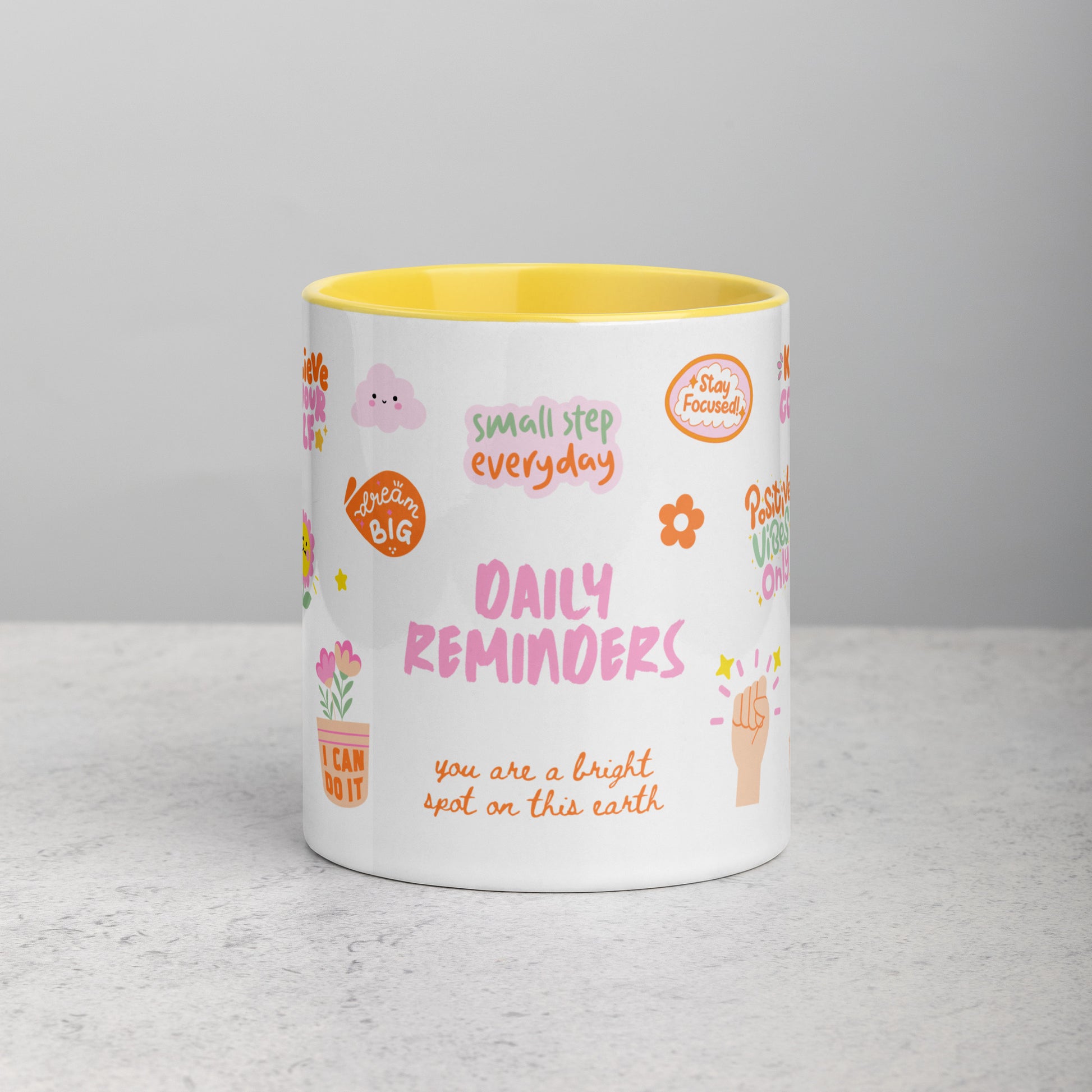 yellow mug with colorful text and graphics on a gray surface