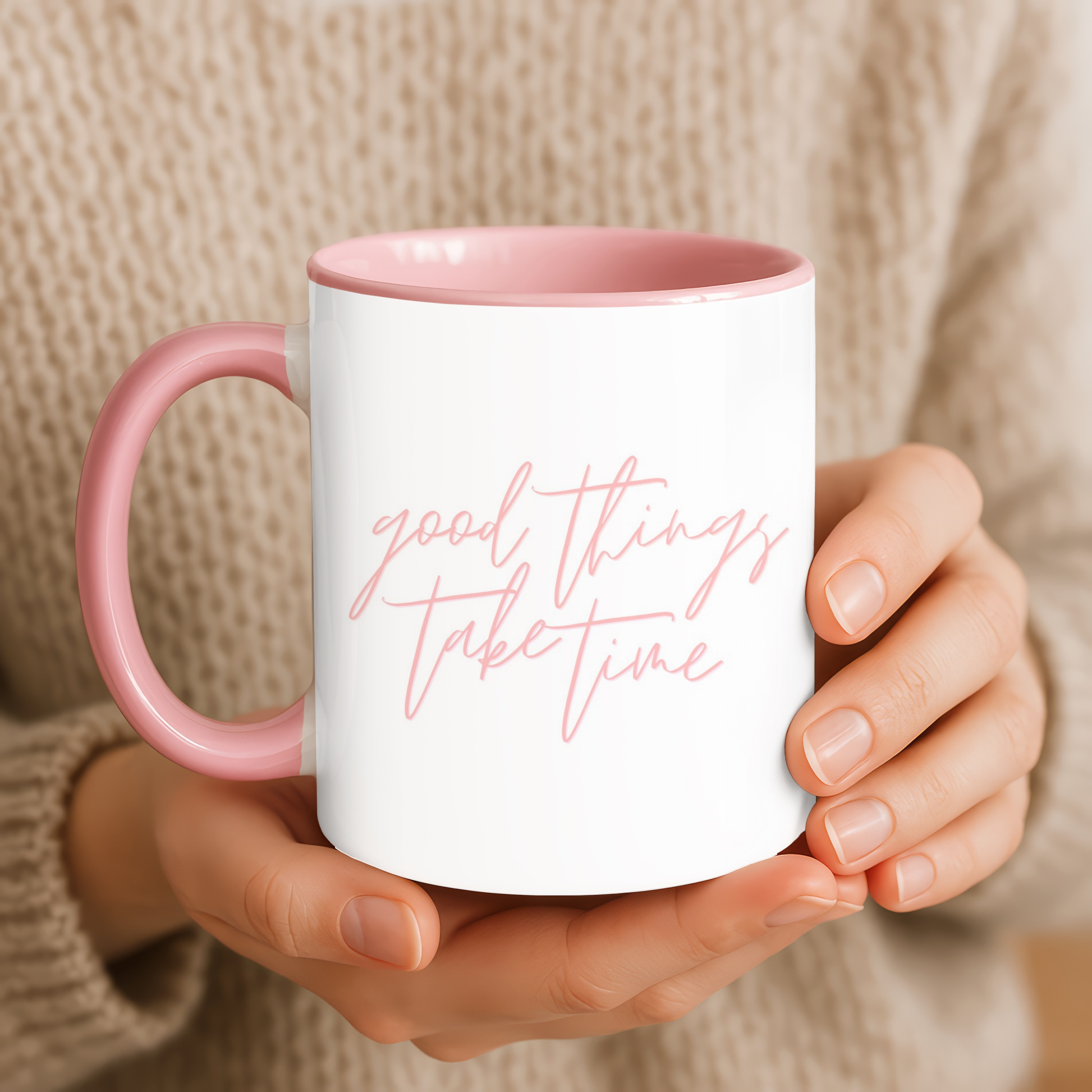 Person holding a white mug with pink interior and handle, featuring the text 'good things take time'.