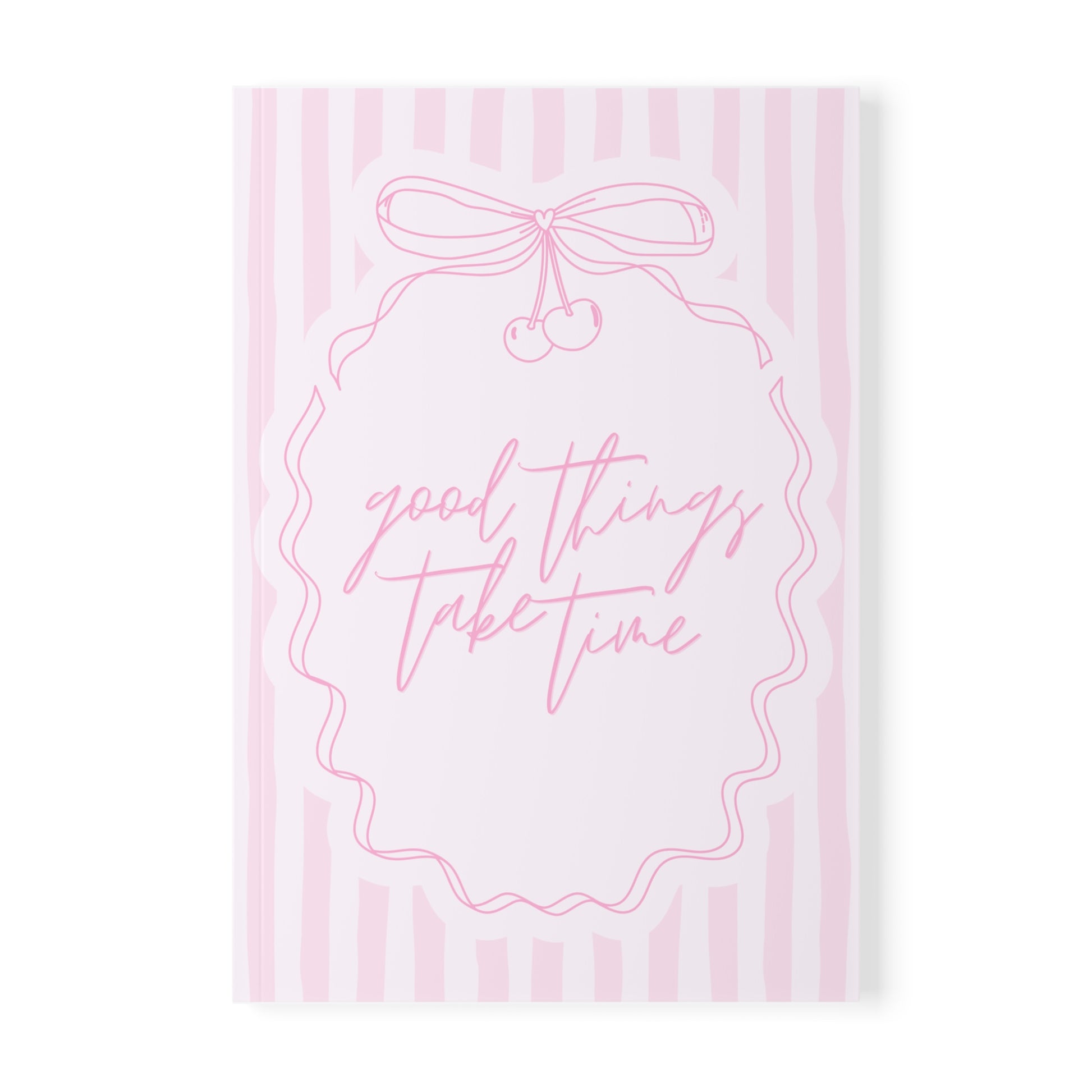 Notebook with 'good things take time' text and a bow design on pink striped background