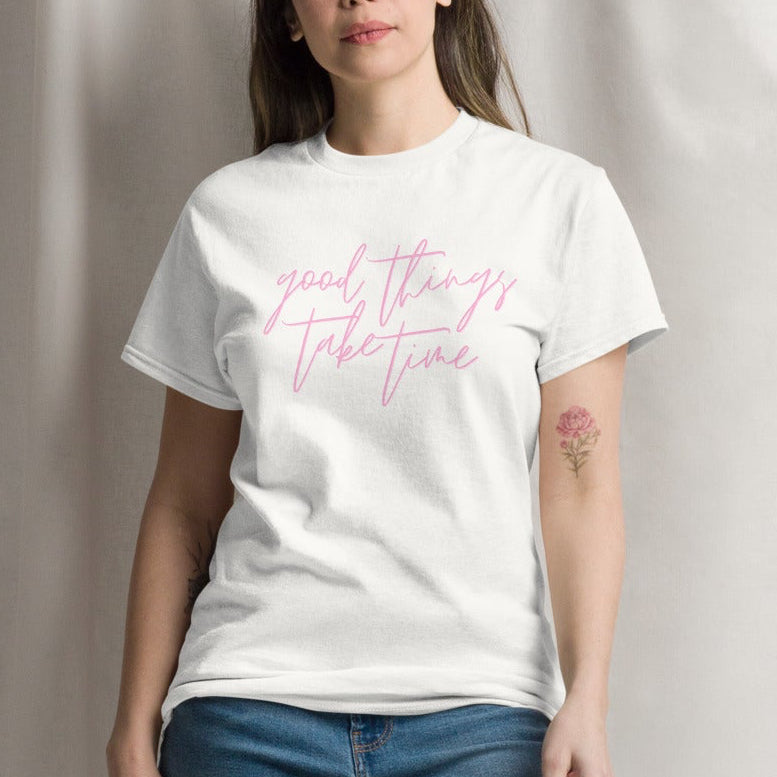 Woman wearing a white t-shirt with text and blue jeans against a plain background