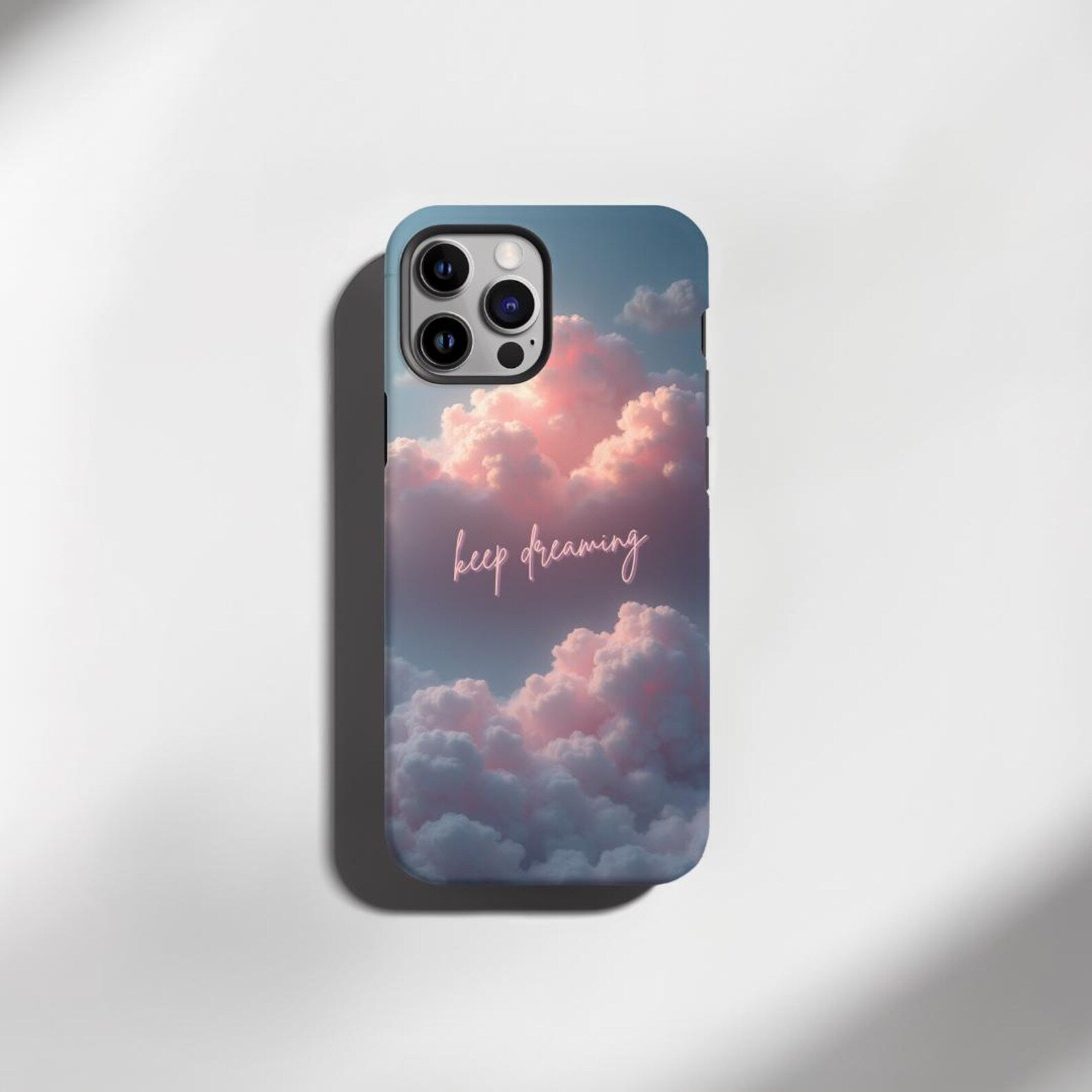 Phone case with cloud design and 'keep dreaming' text on a light gray background