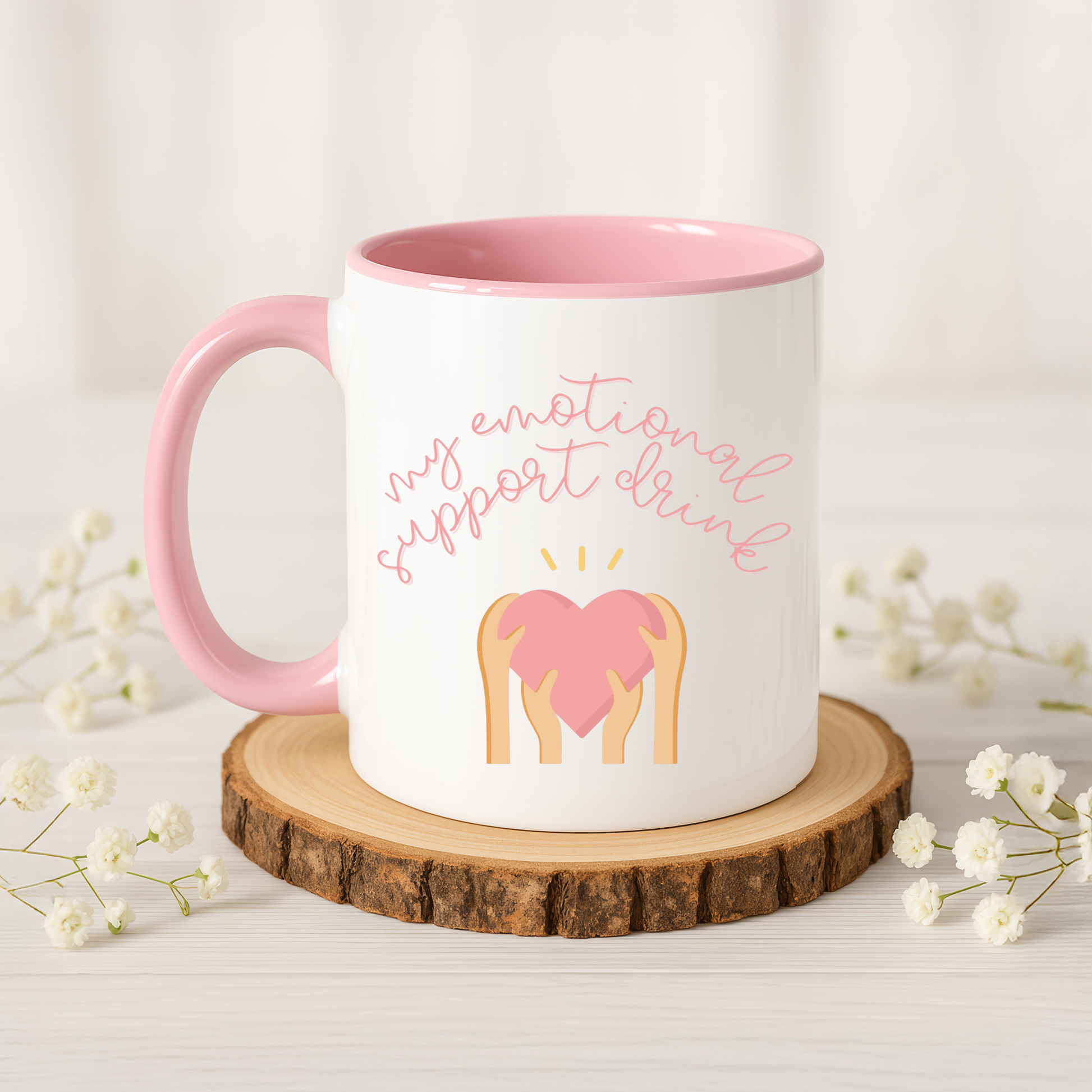 Mug with pink interior and handle, featuring a heart and text on a wooden coaster with flowers.