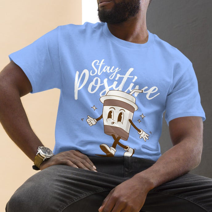 man wearing a blue tshirt with a coffee character and the quote stay positive