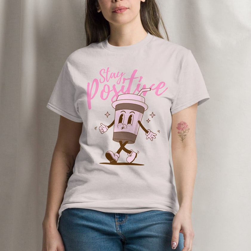woman wearing an ice grey tshirt with a coffee character and the quote stay positive
